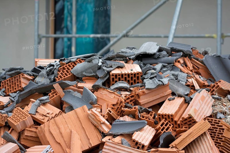 Close-up of mixed construction waste with new building in the background