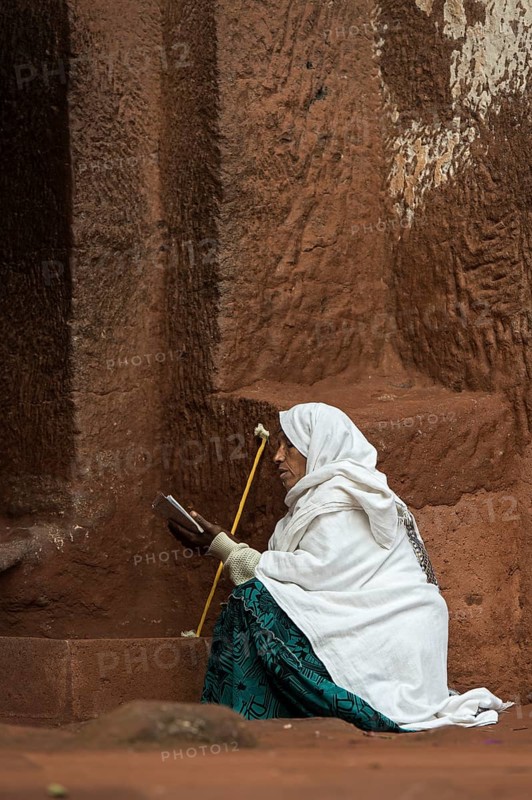 Ethiopian Orthodox woman prays at the entrance to the rock-hewn church of Biete Gabriel-Rufael, Lalibela, Ethiopia, Africa