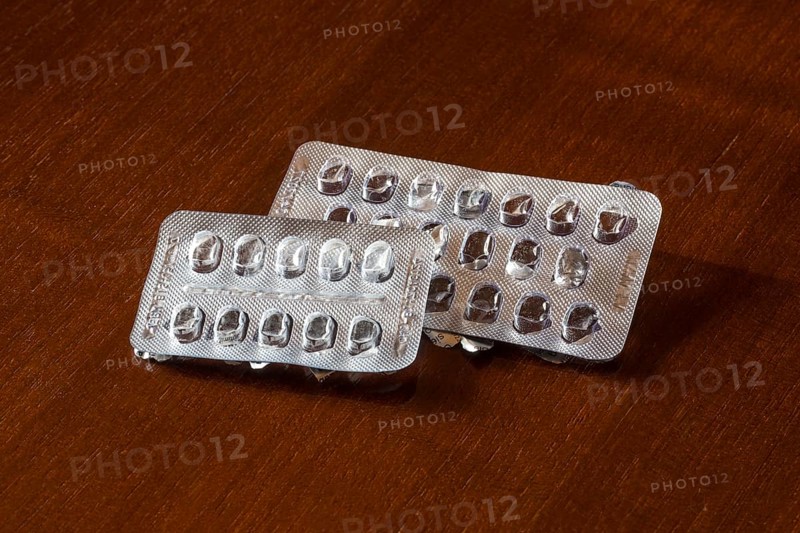 Empty blister packs on a brown wooden surface