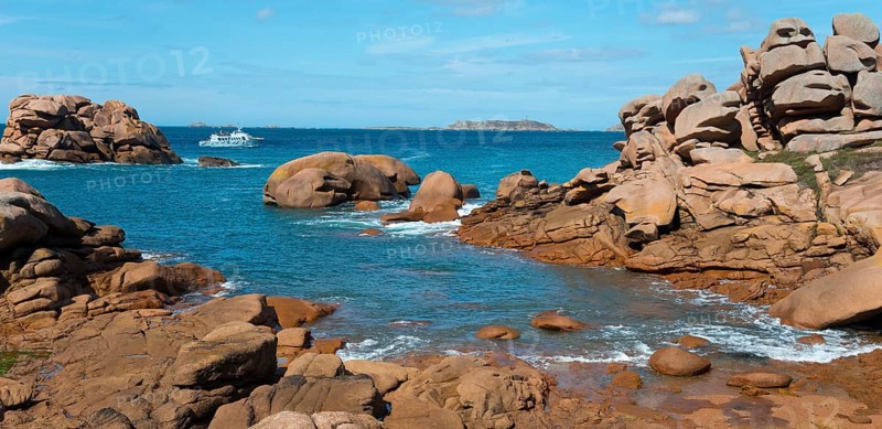 Rocky landscape with blue water and a boat on the horizon, Ploumanac'h, Ploumanach, Perros-Guirec, Côtes-d'Armor, Brittany, France, Europe