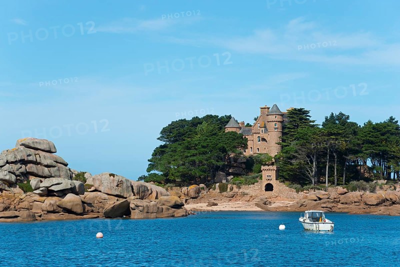 Historic castle on a rocky island surrounded by clear blue sea with a small white boat, granite rocks, Costaeres castle and island, Costaérès, Château de Costaérès, Kostaerez castle, Trégastel, Tregastel, Ploumanac'h, Ploumanach, Cote de Granit Rose, Côte de Granit Rose, Côtes-d'Armor, Brittany, France, Europe