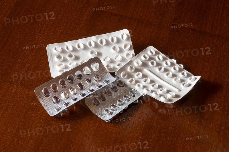 Empty blister packs on a brown wooden surface