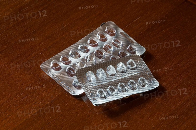 Empty blister packs on a brown wooden surface
