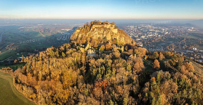 Aerial view of the Hohentwiel volcanic cone with the castle ruins illuminated by the evening sun, behind it the town of Singen am Hohentwiel, Singen am Hohentwiel, Constance district, Baden-Württemberg, Germany, Europe