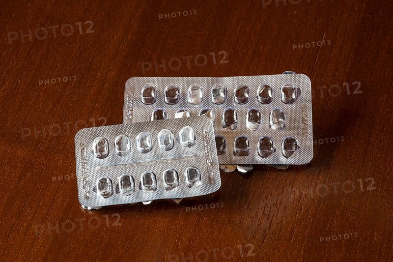 Empty blister packs on a brown wooden surface