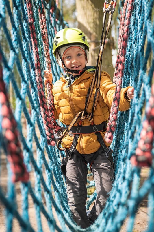 Portrait of cute little boy walk on the net in an adventure rope park