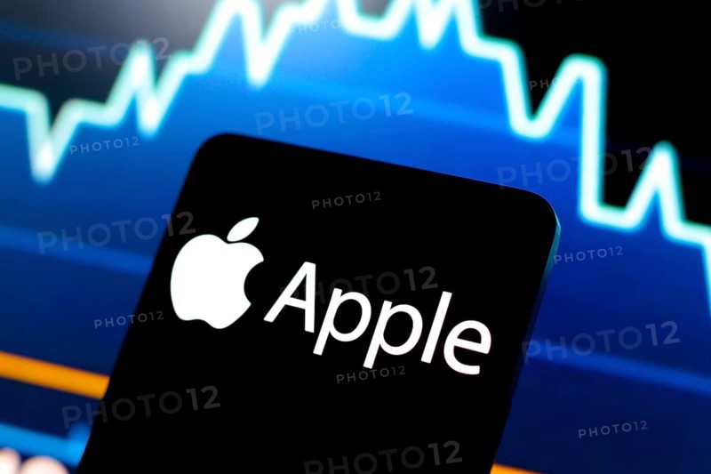 In this photo illustration, the Apple logo is displayed on a smartphone screen and in the background, a stock market graph