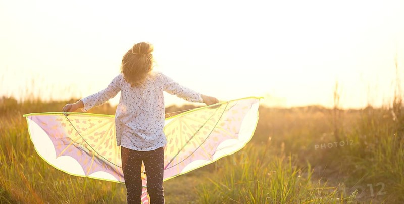 Girl is standing with wings in field, learning to fly a kite, Outdoor entertainment in summer, nature and fresh air. Childhood, freedom and carelessness. Children's dreams and hope