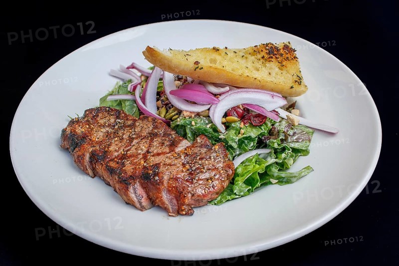 NY Strip steak with brown butter, accompanied by sautéed vegetables and a peppercorn demi-glace with a garlic bread