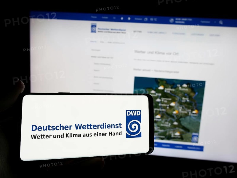 Stuttgart, Germany, 06-06-2024: Person holding smartphone with logo of German meteorological service Deutscher Wetterdienst (DWD) in front of website. Focus on phone display, Europe