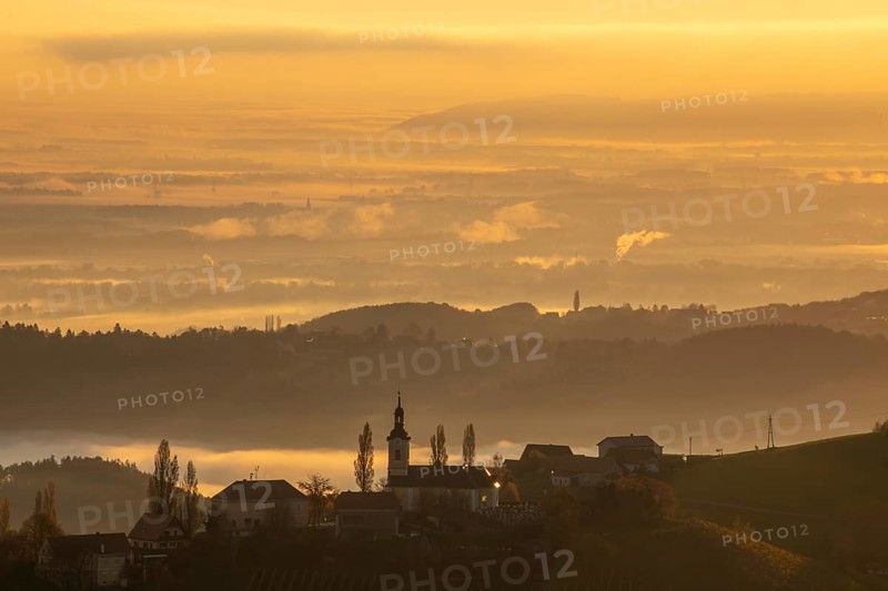 Autumn atmosphere in the golden morning light, fog drifts over the hilly landscape, silhouette of the church of Kitzeck, view from the Demmerkogel viewing platform, St. Andrä-Höch, Sausal wine country, Styria, Austria, Europe