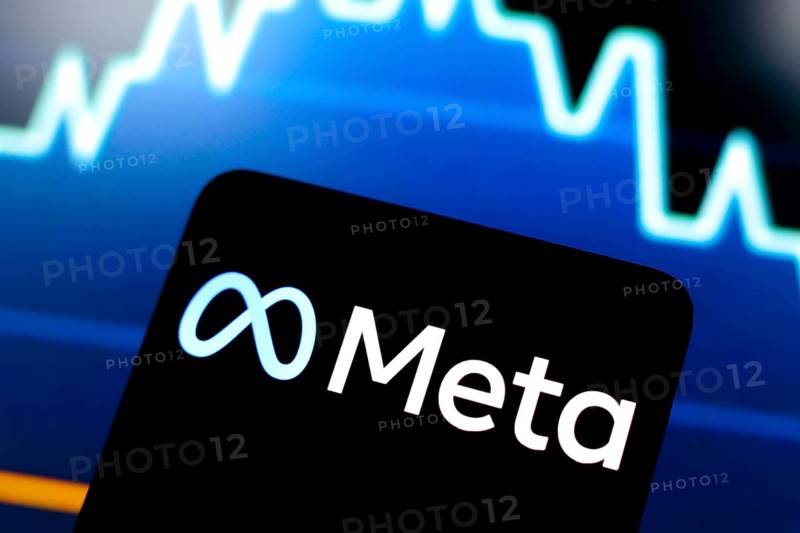 In this photo illustration, the Meta logo is displayed on a smartphone screen and in the background, a stock market graph