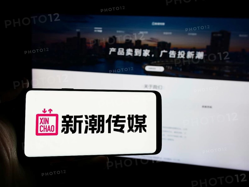 Stuttgart, Germany, 07-11-2024: Person holding mobile phone with logo of advertising company Chengdu Xinchao Media Group Co. Ltd. in front of web page. Focus on phone display, Europe