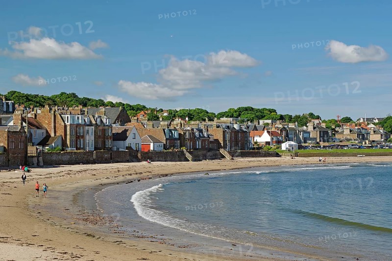 Houses along a beach with walkers by the sea under a blue sky on a sunny day, North Berwick, Scotland, United Kingdom, Europe