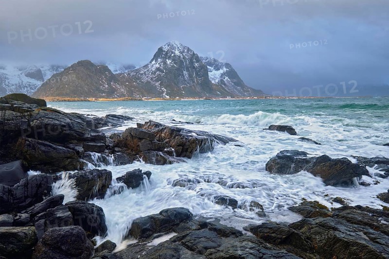 Waves crushing on rocks on rocky coast of fjord of Norwegian sea in winter. Lofoten islands, Norway, Europe