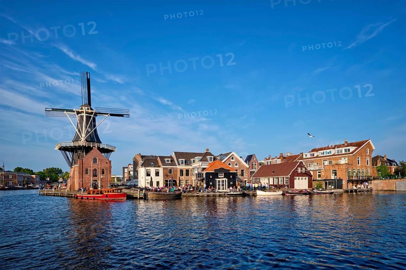 Harlem cityscape, landmark windmill De Adriaan on Spaarne river with boats. Harlem, Netherlands