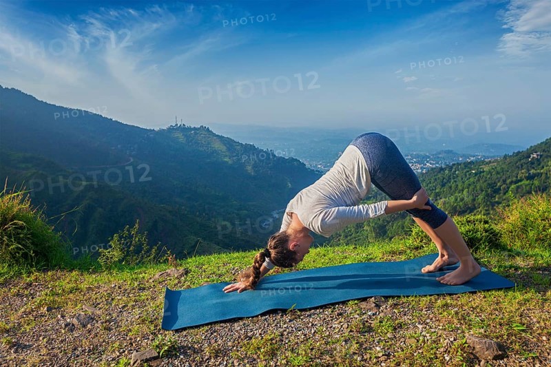 Yoga outdoors, young sporty fit woman doing Ashtanga Vinyasa Yoga asana Adho mukha svanasana, downward facing dog variation, outdoors in Himalayas in the morning