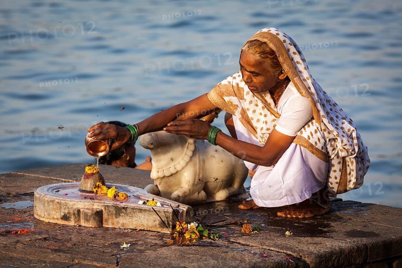 MAHESHWAR, INDIA, APRIL 26: Indian woman performs morning pooja on sacred river Narmada ghats on April 26, 2011 in Maheshwar, Madhya Pradesh, India. To Hindus Narmada is one of 5 holy rivers of India