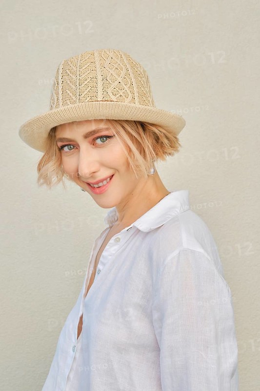 Lifestyle portrait of tricky young woman with healthy skin in white shirt and straw hat