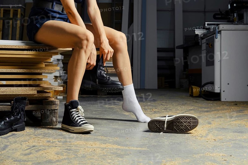 Female legs in carpenter shop, change of footwear