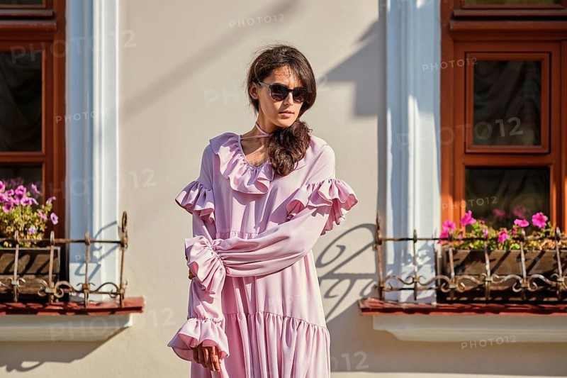 Outdoor urban portrait of young beautiful stylish girl in oversized pink dress