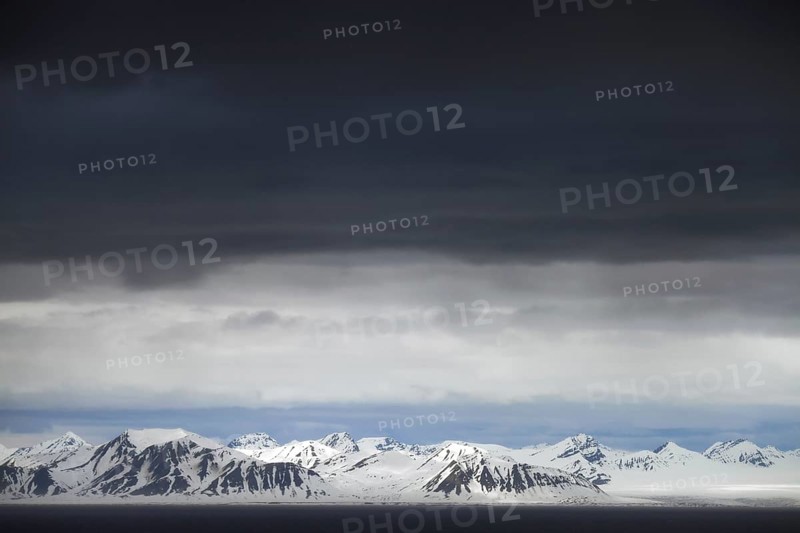 Black rain clouds over snow covered mountains along Isfjorden, second longest fjord at Spitsbergen, Svalbard