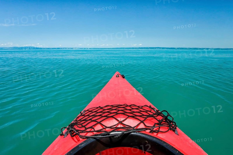 Bow of red kayak with view over the expanse and turquoise waters of Lake Constance