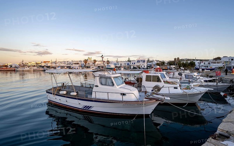 Fishing boats in the harbour of Naoussa at sunset, reflected in the sea, White Cycladic houses, Naoussa, Paros, Cyclades, Greece, Europe