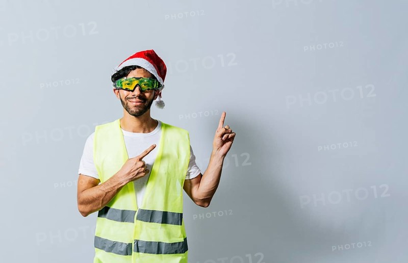 Construction worker with christmas hat pointing to an advertisement. Builder worker with christmas hat pointing a finger at a promotion. Builder engineer in christmas hat pointing to the right, Managua, Nicaragua, Central America