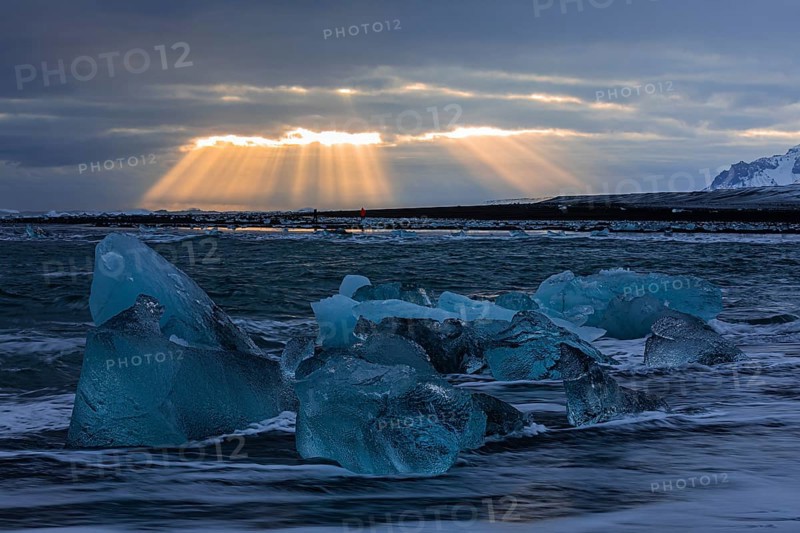Waves breaking on icebergs on the black beach of Breidamerkursandur, sunset, near Jökullsarlon, Sudurland, Iceland, Europe