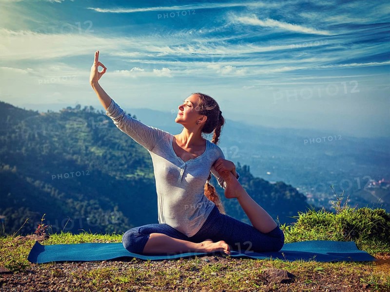 Yoga outdoors, young sporty fit woman doing stretching yoga asana Eka pada rajakapotasana, one-legged king pigeon pose in Himalayas mountains, India. Vintage retro effect filtered hipster style image