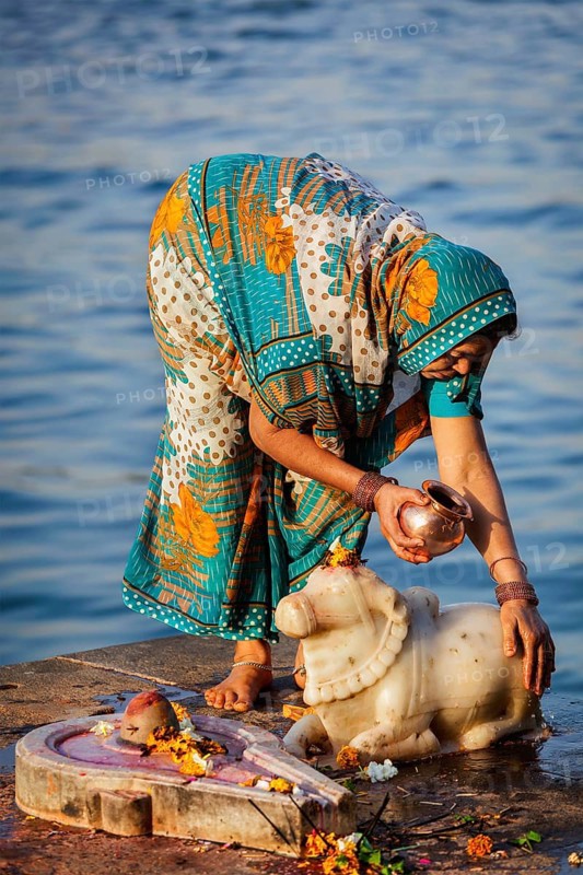 MAHESHWAR, INDIA, APRIL 26: Indian woman performs morning pooja on sacred river Narmada ghats on April 26, 2011 in Maheshwar, Madhya Pradesh, India. To Hindus Narmada is one of 5 holy rivers of India