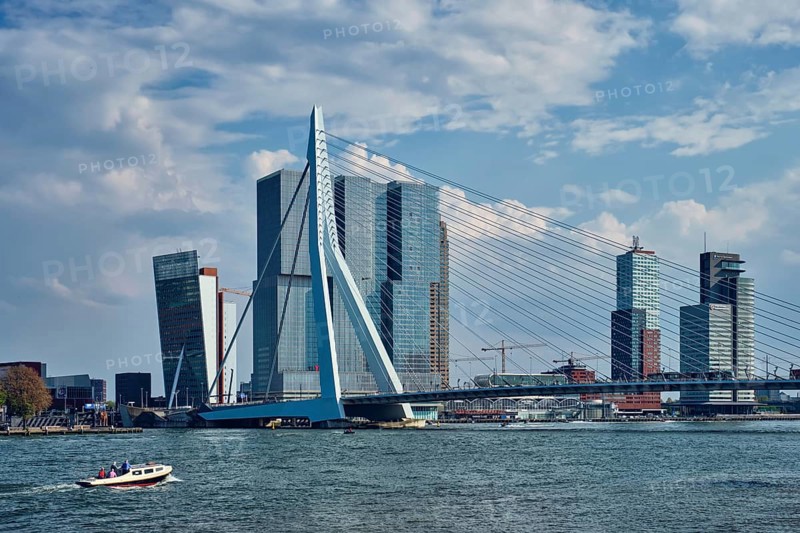 ROTTERDAM, THE NETHERLANDS, MAY 11, 2017: View of Rotterdam sityscape with Erasmusbrug bridge over Nieuwe Maas and modern architecture skyscrapers with speed boat passing uner the bridge