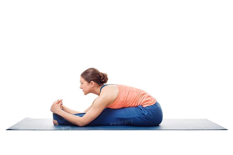 Sporty fit woman doing Ashtanga Vinyasa yoga back bending asana Paschimottanasana, seated forward bend isolated on white