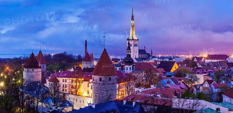 Panorama of aerial view of Tallinn Medieval Old Town with St. Olaf's Church and Tallinn City Wall illuminated in evening, Estonia, Europe