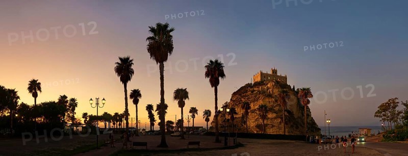 Parking with palm trees overlooking the medieval church Santuario di Santa Maria dell Isola di Tropea built on rocks of sandstone at sunset, Tropea, Calabria, Vibo Valentia, Southern Italy, Italy, Europe