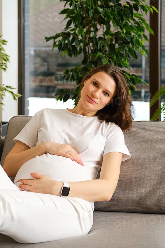 Beautiful pregnant woman having rest on sofa at home