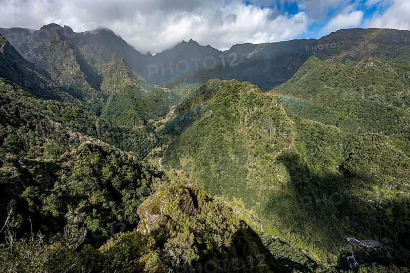 Densely overgrown steep mountains with rainbow, green mountain landscape, view from Miradouro dos Balcões, mountain valley Ribeira da Metade and the central mountains, Madeira, Portugal, Europe