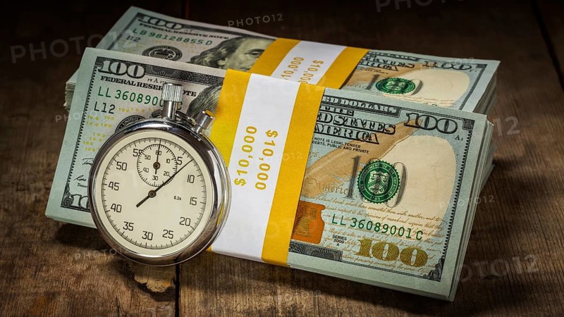 Time is money loan concept background, letterbox panorama of stopwatch and stack of new 100 US dollars 2013 edition banknotes (bills) bundles on wooden background