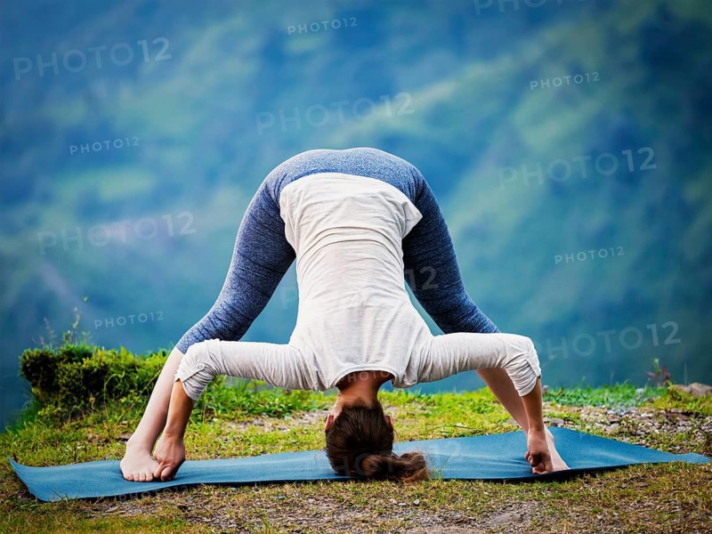Yoga exercise outdoors, woman doing Ashtanga Vinyasa Yoga asana Prasarita padottanasana D, wide legged forward bend pose outdoors. Vintage retro effect filtered hipster style image