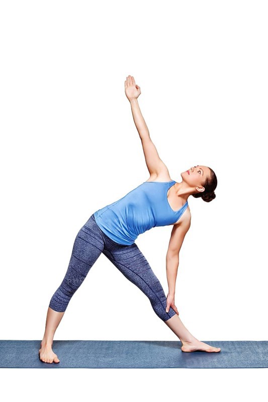 Beautiful sporty fit woman practices yoga asana utthita trikonasana, extended triangle pose beginner variation isolated on white