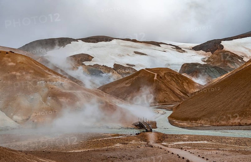 Bridge and steaming streams between colourful rhyolite mountains and snowfields, Hveradalir geothermal area, Kerlingarfjöll, Icelandic Highlands, Iceland, Europe