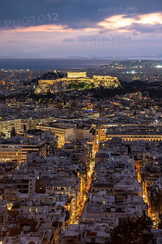 View over the sea of houses of Athens, illuminated Parthenon temple on the Acropolis, dramatic cloudy sky, from Mount Lycabettus, Athens, Greece, Europe