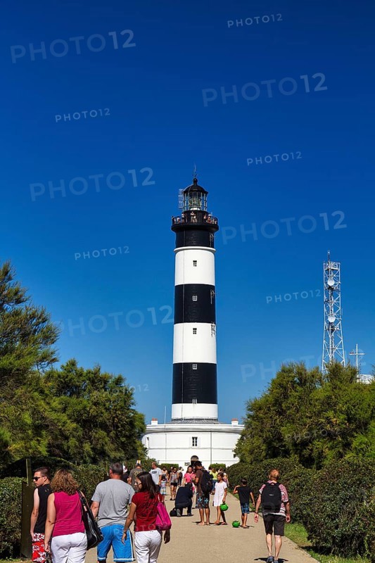 Pedestrians in the garden at the black and white Chassiron lighthouse, Saint-Denis-dOléron, Oleron Island, France, Europe