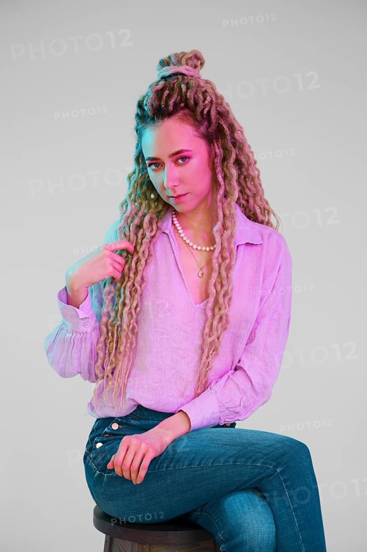 Young woman touching her dreadlocks and looking forward