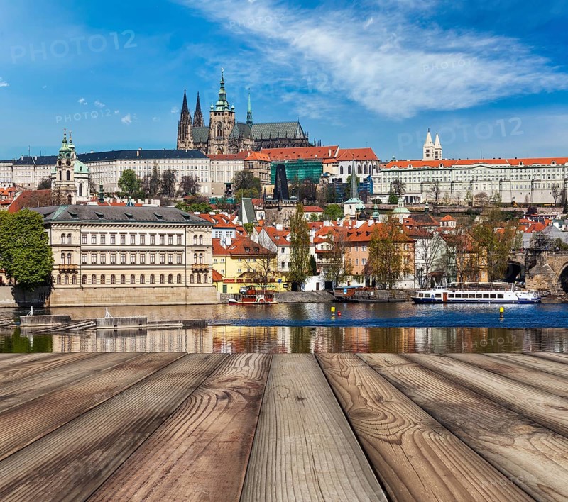 Wooden planks vith view of Prague Charles bridge over Vltava river and Gradchany (Prague Castle) and St. Vitus Cathedral in background