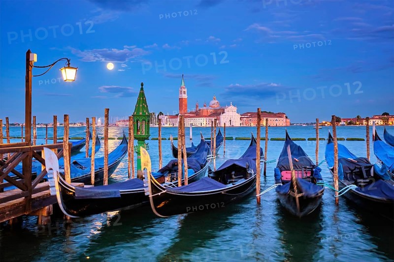 Romantic vacation Venice travel background, gondolas at Saint Mark (San Marco) square and Basilica San Giorgio Maggiore Church seen across Venice lagoon with full moon. Venice, Italy, Europe