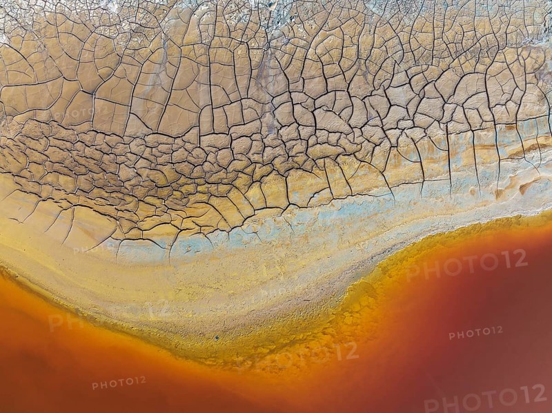 Cracked earth at the bank of the Rio Tinto (Red river) with its deep reddish hue due to oxidised iron minerals in its water, aerial view, drone shot, Huelva province, Andalusia, Spain, Europe