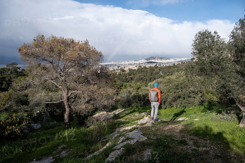 Tourist looking over the city with rainbow, Philopappos Hill, in the evening light, Athens, Attica, Greece, Europe