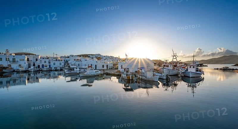 Fishing boats in the harbour of Naoussa at sunset, reflected in the sea, Sun star, White Cycladic houses, Naoussa, Paros, Cyclades, Greece, Europe